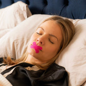 A woman sleeping peacefully while wearing Lunasol Sleep Barely There Mouth Tape in Sunset Pink, promoting nasal breathing for deeper, more restorative sleep.