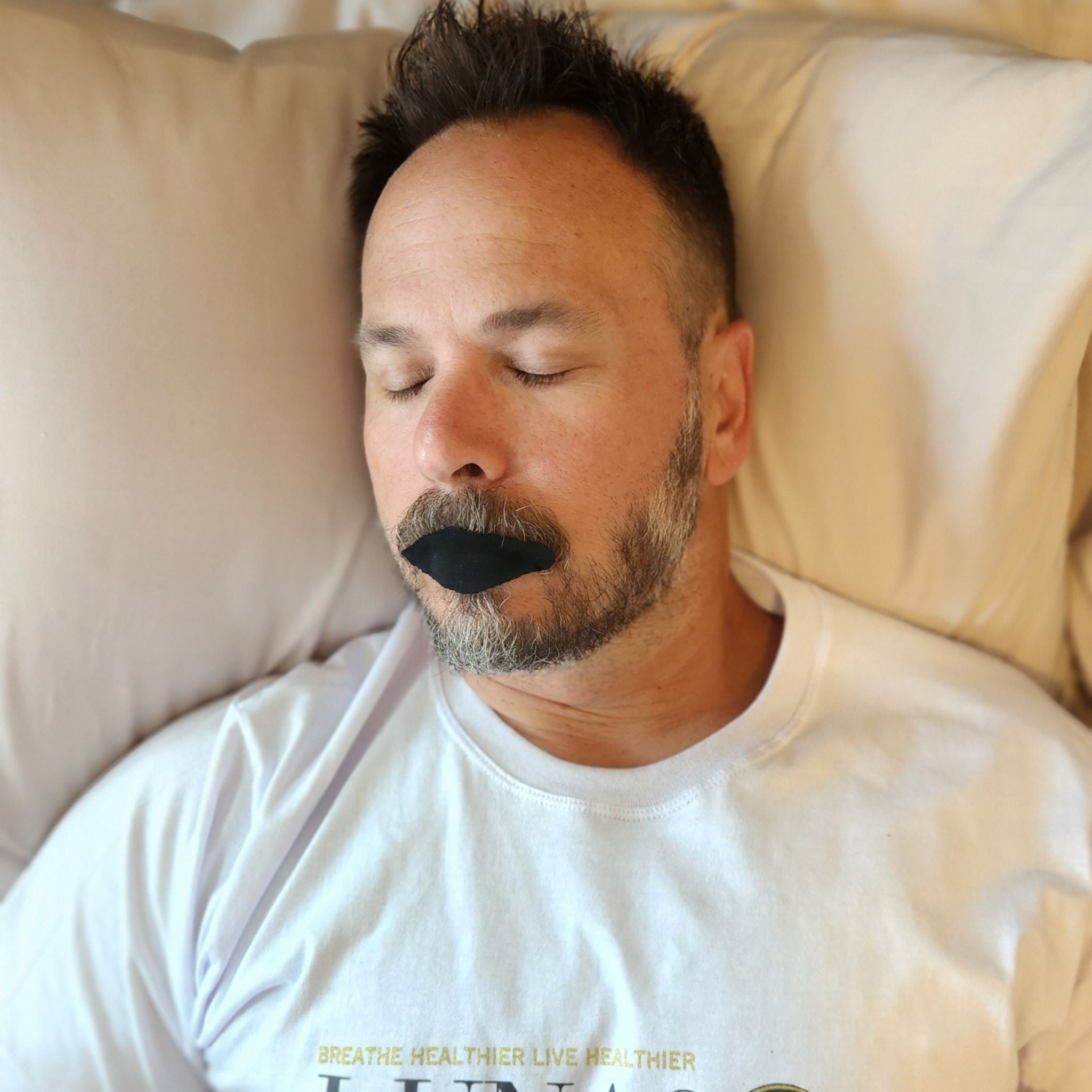 A man sleeping soundly while wearing Lunasol Sleep Just the Lips Mouth Tape in Eclipse Black, promoting nasal breathing for improved sleep quality and overall health.